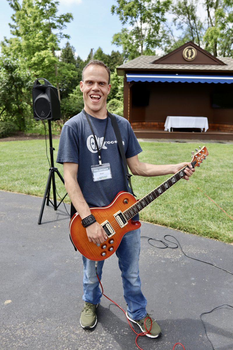 Sean smiling and playing his guitar